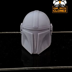 Puede incluir: Un casco mandaloriano de pl&aacute;stico gris para una figura de acci&oacute;n a escala 1/6. El casco tiene una superficie texturizada y est&aacute; dise&ntilde;ado para parecerse al casco que lleva el personaje de la serie Star Wars.
