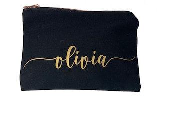 May include: Black canvas zippered pouch with a gold cursive inscription that reads "olivia".