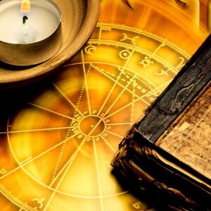 Peut inclure: Une bougie allum&eacute;e dans un bougeoir en c&eacute;ramique brune repose sur une carte astrologique jaune et or avec un livre reli&eacute; en cuir vintage.