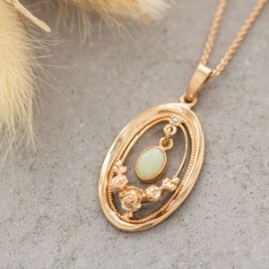 May include: A gold pendant necklace with an oval-shaped opal gemstone. The pendant features a delicate floral design and a small diamond accent.
