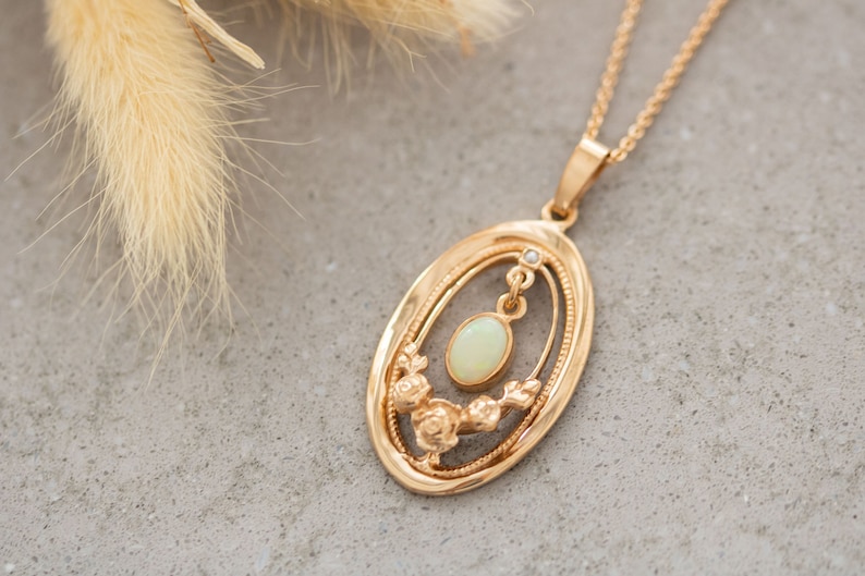 May include: A gold pendant necklace with an oval-shaped opal gemstone. The pendant features a delicate floral design and a small diamond accent.