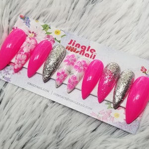 May include: Set of artificial nails in various designs. Some nails are bright pink, others are silver glitter, and some feature a floral pattern. The nails are displayed on a card with the text "Jingle Nail" and website information.