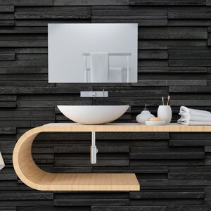 Puede incluir: Un tocador de ba&ntilde;o moderno con un lavabo de cer&aacute;mica blanca, una encimera de madera y un espejo sobre el lavabo. El tocador est&aacute; montado en una pared de azulejos negros.