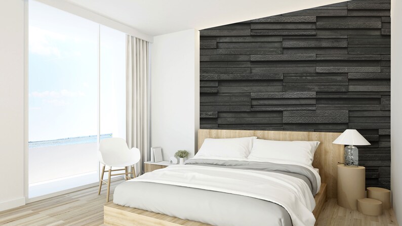 Puede incluir: Un dormitorio blanco con una gran ventana con vistas al oc&eacute;ano. La cama tiene una cabecera blanca y una funda n&oacute;rdica blanca. Una pared de piedra negra est&aacute; detr&aacute;s de la cama. Una silla blanca est&aacute; en la esquina de la habitaci&oacute;n.