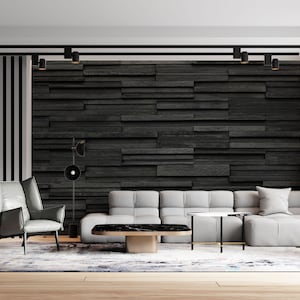 Puede incluir: Un sal&oacute;n moderno con un sof&aacute; de esquina gris, un sill&oacute;n gris y una mesa de centro negra. La pared detr&aacute;s del sof&aacute; est&aacute; cubierta de azulejos de pizarra negra. La habitaci&oacute;n tiene un suelo de madera y una alfombra.