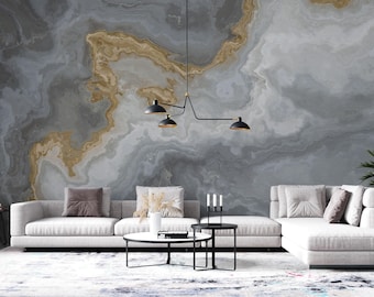 Puede incluir: Un mural de pared a gran escala con un patrón de mármol arremolinado en tonos gris, blanco y dorado. El diseño cubre toda la pared detrás de un sofá seccional blanco, dos mesas de centro redondas y una lámpara colgante negra de tres luces.