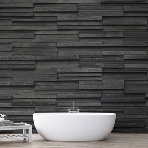 Puede incluir: Una ba&ntilde;era blanca independiente en un ba&ntilde;o moderno con una pared de piedra negra detr&aacute;s.