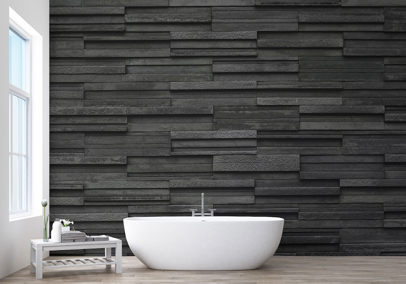 Puede incluir: Una ba&ntilde;era blanca independiente en un ba&ntilde;o moderno con una pared de piedra negra detr&aacute;s.