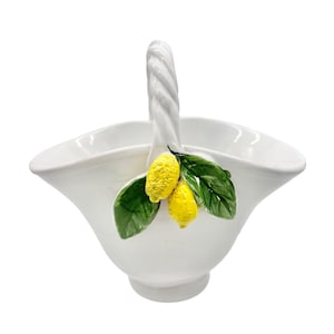 May include: White ceramic basket with a twisted handle and a lemon motif. The basket is decorated with three yellow lemons and green leaves.