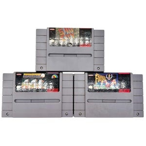 May include: Three gray Super Nintendo game cartridges stacked. The top cartridge has a label with the text "Final City". The middle cartridge is labeled "MVP Baseball" and the bottom cartridge is labeled "Football".