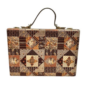 Pode incluir: Uma mala retangular vintage com um design de patchwork em tons de castanho, bege e laranja. A mala apresenta uma pega superior e ferragens metálicas. O padrão de patchwork inclui motivos florais e geométricos.