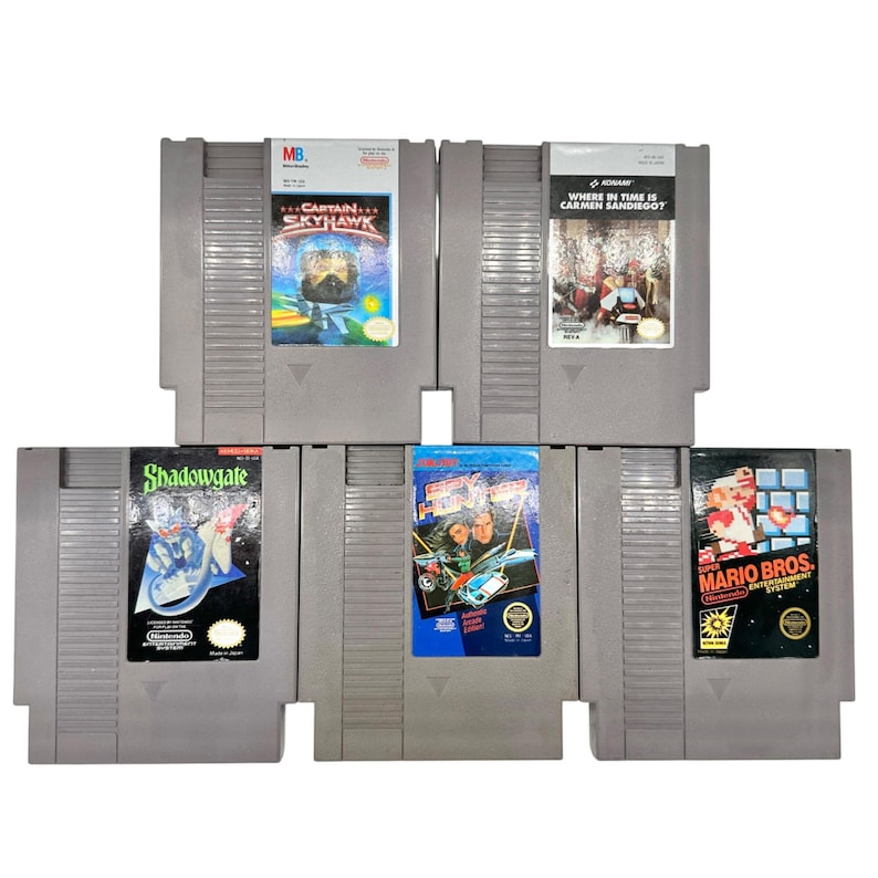 Pode incluir: Uma cole&ccedil;&atilde;o de cinco cartuchos de videojogos Nintendo Entertainment System (NES). Os jogos incluem "Captain Skyhawk", "Where in Time is Carmen Sandiego?", "Shadowgate", "Top Gun" e "Mario Bros". Os cartuchos s&atilde;o cinzentos com etiquetas coloridas de arte de jogo.