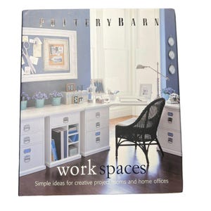 May include: A Pottery Barn book cover featuring a home office scene. The cover displays a white desk and cabinets, a black wicker chair, and a blue wall. The text "work spaces" and "Simple ideas for creative project rooms and home offices" are visible.