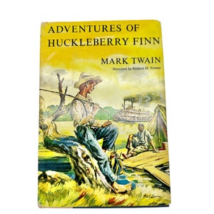 Puede incluir: Una portada de libro de bolsillo vintage con una ilustración de un niño con un sombrero de paja pescando desde una rama de árbol. El título del libro es "Las Aventuras de Huckleberry Finn" de Mark Twain. La portada es amarilla con una ilustración verde y marrón.
