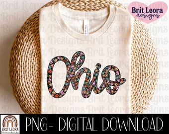 May include: A white t-shirt featuring a floral design spelling out "Ohio". The design is in shades of pink, blue, and green.