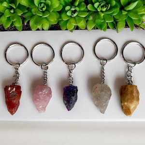 May include: Five different crystal keychains with silver key rings and chains. The crystals are red, pink, purple, clear, and yellow.