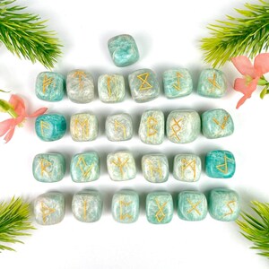 Peut inclure: Ensemble de 25 pierres de runes en amazonite verte avec des runes dorées. Chaque pierre est de forme cubique avec un symbole de rune différent.