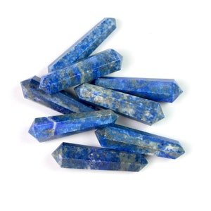 May include: A group of six blue lapis lazuli crystal points, also known as wands, are arranged in a pile on a white background.