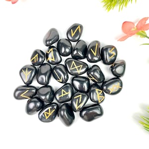 Peut inclure: Un ensemble de 20 pierres d'obsidienne noire avec des runes dorées inscrites sur chacune. Les pierres sont polies et lisses.