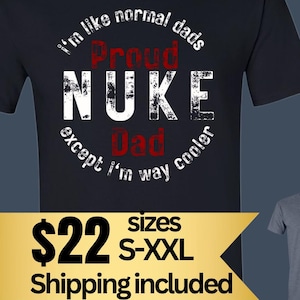 May include: Black t-shirt with the text "I'm like normal dads Proud NUKE Dad except I'm way cooler." The shirt also has the text "Proud Nuke Dad Shirt Available in:" and is available in black, heather navy, and navy.
