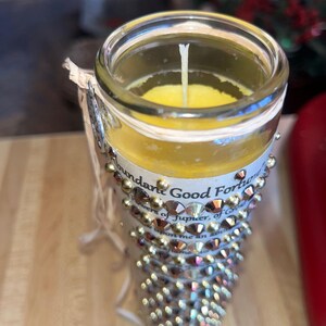 K&ouml;nnte beinhalten: Ein klares Glasgef&auml;&szlig; mit einer gelben Kerze darin. Das Gef&auml;&szlig; ist mit goldenen Strasssteinen verziert und tr&auml;gt ein Etikett mit der Aufschrift "Abundant Good Fortune, Powers of Jupiter, of Greatness, bestow upon me an abundance of..."