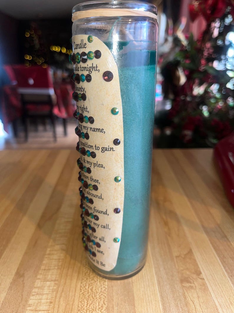 May include: A teal green candle with a label that reads "Candle tonight, munty, right, my name, position to gain. my plea, en thee, abound, en found, my call. fter all, ... Make it Be". The label is decorated with small, colorful rhinestones.
