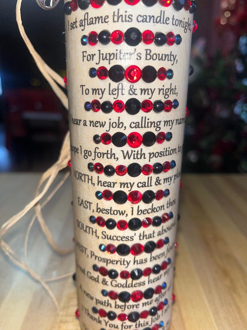 May include: A beige candle with a red and black design. The candle has a text inscription that reads: "set aflame this candle tonight For Jupiter's Bounty, To my left & my right, I hear a new job, calling my name. Hope I go forth, With position to WORTH, hear my call & my place EAST, bestow, I beckon there SOUTH, Success' that abounds WEST, Prosperity has been found. Let God & Goddess hear my plea A new path before me after this. Thank You for this job."