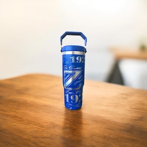 Può includere: Un bicchiere in acciaio inossidabile blu con un manico argentato e un design argentato che dice "Zeta Phi 1922 So Sweet" con cuori e una grande lettera Z.
