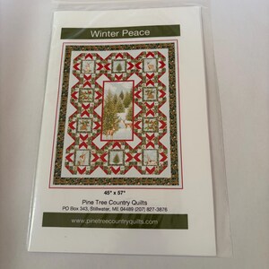May include: A quilt pattern titled Winter Peace featuring a central panel of deer in a snowy forest surrounded by blocks of red and green geometric shapes and wildlife imagery. The pattern measures 45 inches by 57 inches and includes contact information for Pine Tree Country Quilts.
