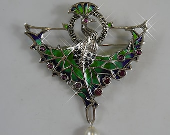 Puede incluir: Broche plateado con diseño de pavo real, alas esmaltadas en verde y azul, acentuado con piedras rojas. El pavo real está posado dentro de un halo con incrustaciones de marcasita, y una perla colgante añade elegancia. Joya decorativa.