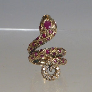 May include: A gold ring shaped like a coiled snake with red ruby stones and a diamond-encrusted tail.