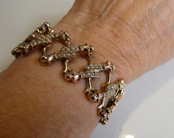 Puede incluir: Un brazalete de oro con un diseño único que presenta eslabones entrelazados adornados con pequeñas perlas blancas.