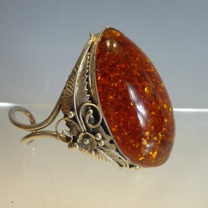 May include: A silver ring with an amber stone set in a floral design.