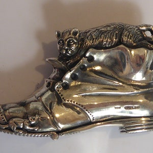 May include: A silver boot with a cat sitting on top of it. The boot has a small mouse on the side. The boot is marked "Sterling".