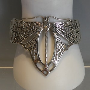 Può includere: Braccialetto d'argento con un design a libellula. La libellula è realizzata in metallo traforato intricato e ha un aspetto delicato e arioso.