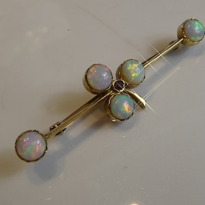 May include: A gold brooch with a clover design set with five opals and a single ruby.