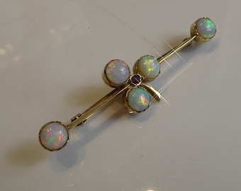 May include: A gold brooch with a clover design set with five opals and a single ruby.