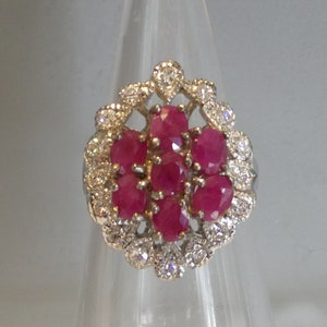 May include: A silver ring featuring a cluster of pink rubies set within a halo of small diamonds.
