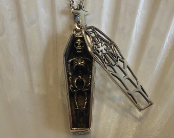 May include: Silver necklace with a coffin pendant featuring a skeleton inside and a separate coffin lid with a spiderweb design.