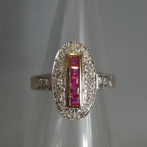 May include: A silver ring with a gold band set with a row of pink square-shaped gemstones surrounded by smaller white gemstones.