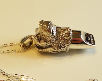 May include: Silver dog whistle necklace with a detailed dog head pendant. The whistle is engraved with "STERLING SILVER 925".