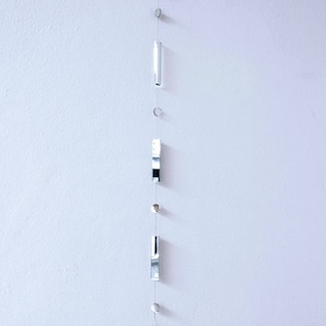 May include: A silver mobile hanging from a white ceiling with a white background. The mobile has a variety of shapes, including circles, squares, and rectangles.