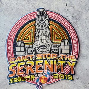 Puede incluir: Parche bordado con un diseño de nave espacial y el texto "CAN'T STOP THE SERENITY" y "2019". El parche tiene un borde circular con un patrón decorativo y caracteres chinos.
