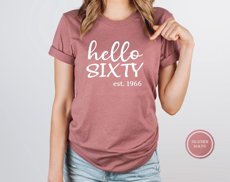 A woman wearing a pink t-shirt with the text "Hello SIXTY" printed on it.