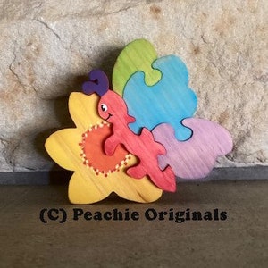 May include: A colorful wooden puzzle featuring a butterfly with a flower. The butterfly is red, blue, and purple, and the flower is yellow with orange accents. The puzzle is made of interlocking pieces.