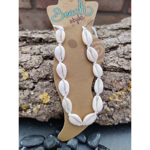 Könnte beinhalten: Weißes Muschel-Anklett mit weißem Band und braunem Etikett mit der Aufschrift "Beach style".