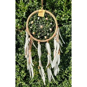 May include: A brown dream catcher with white feathers and a white beaded web. The dream catcher has a small tag that says "Dream Catcher".