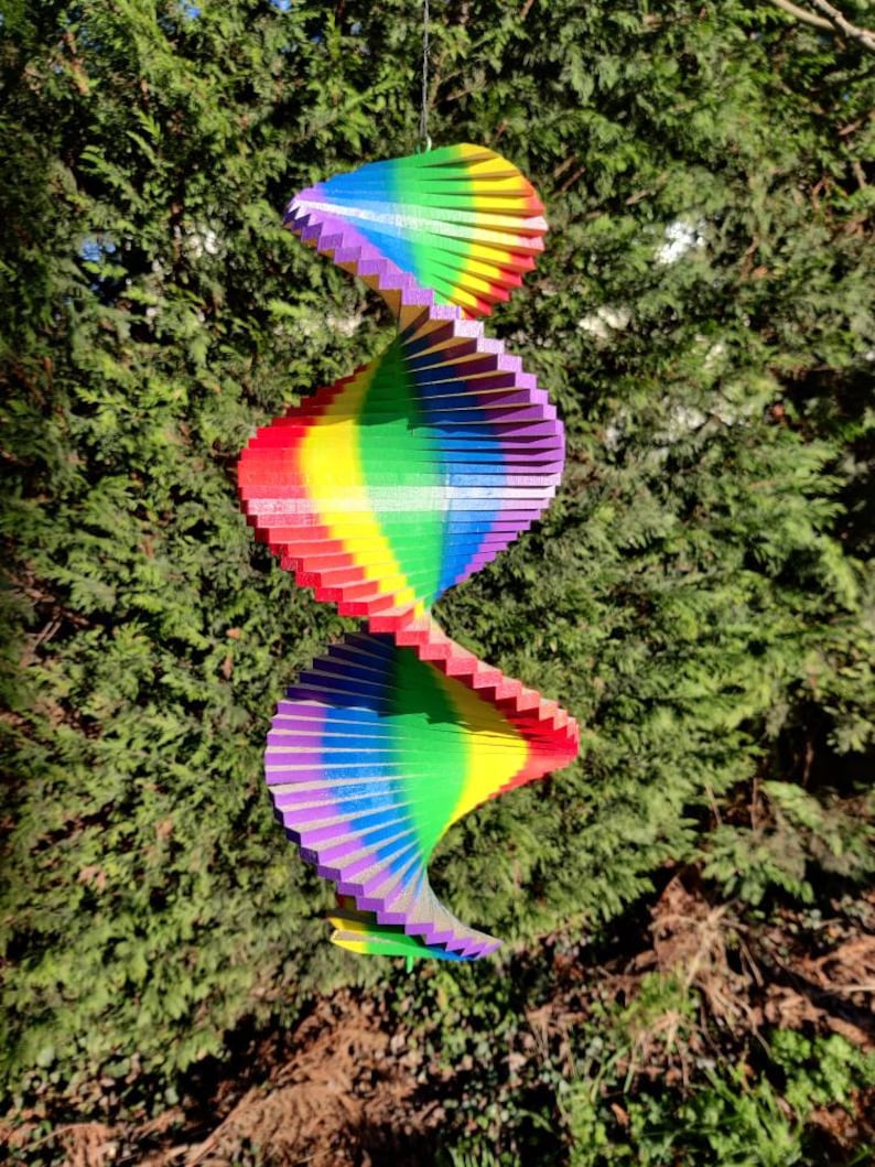 Pu&ograve; includere: Un mulino a vento arcobaleno colorato con tre livelli di lamelle di legno. Il mulino &egrave; sospeso a una corda ed &egrave; progettato per ruotare al vento.