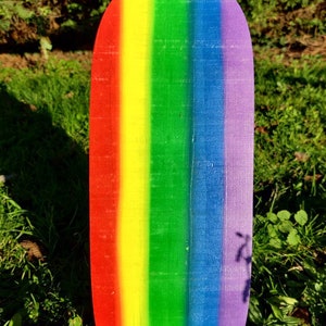 Pu&ograve; includere: Un pannello di legno arrotondato dipinto con i colori dell'arcobaleno. Il pannello &egrave; dipinto con strisce rosse, arancioni, gialle, verdi, blu, indaco e viola.