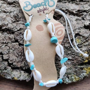 May include: White and turquoise shell anklet with a white string and a brown tag that says "Hand Made Beach Style".